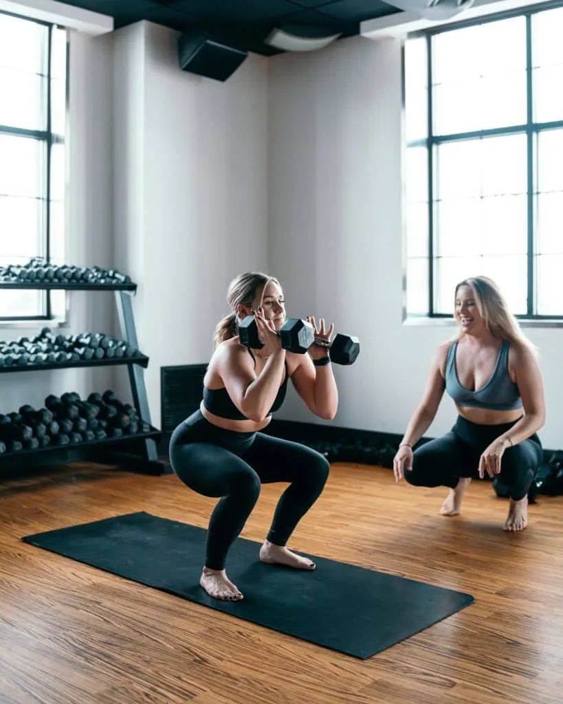Personne effectuant un squat avec un haltère dans une salle de sport