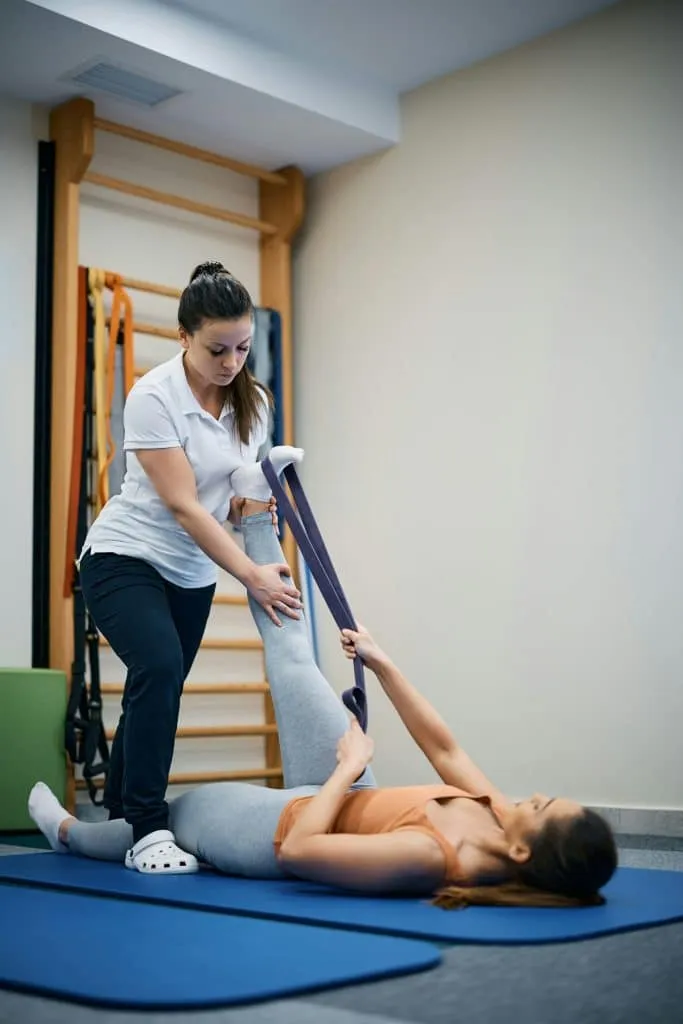 Deux personnes réalisant un mouvement de jambe avec une sangle sur un tapis
