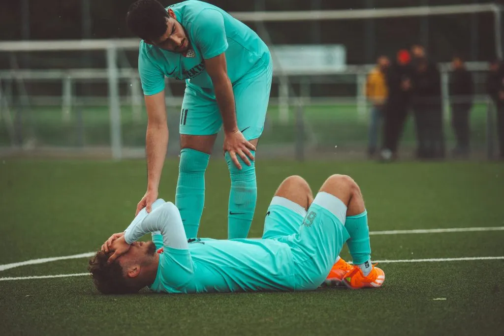 Joueur de football allongé sur le terrain près de son coéquipier