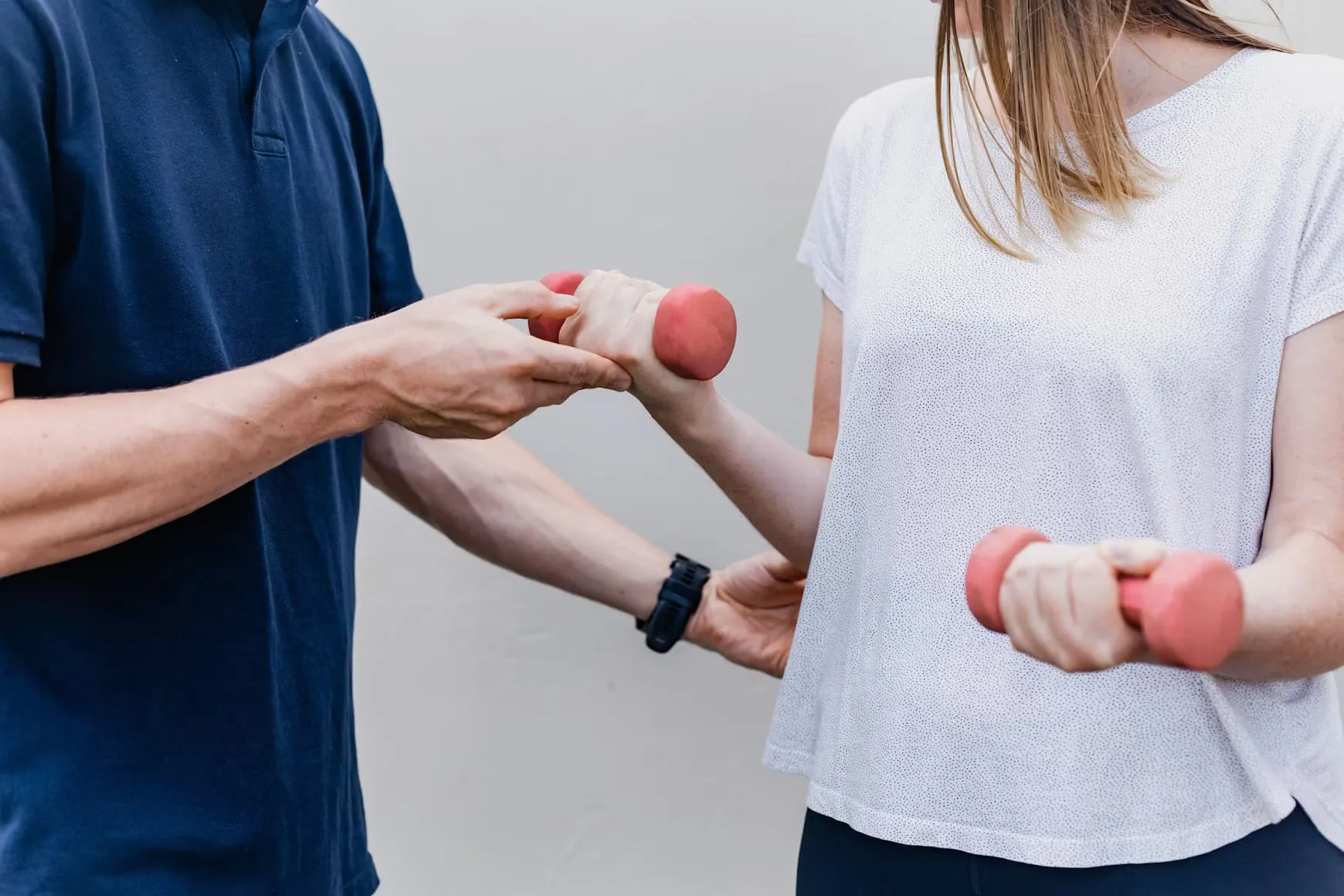 Une personne tient de petits haltères pendant qu’un professionnel lui montre le mouvement