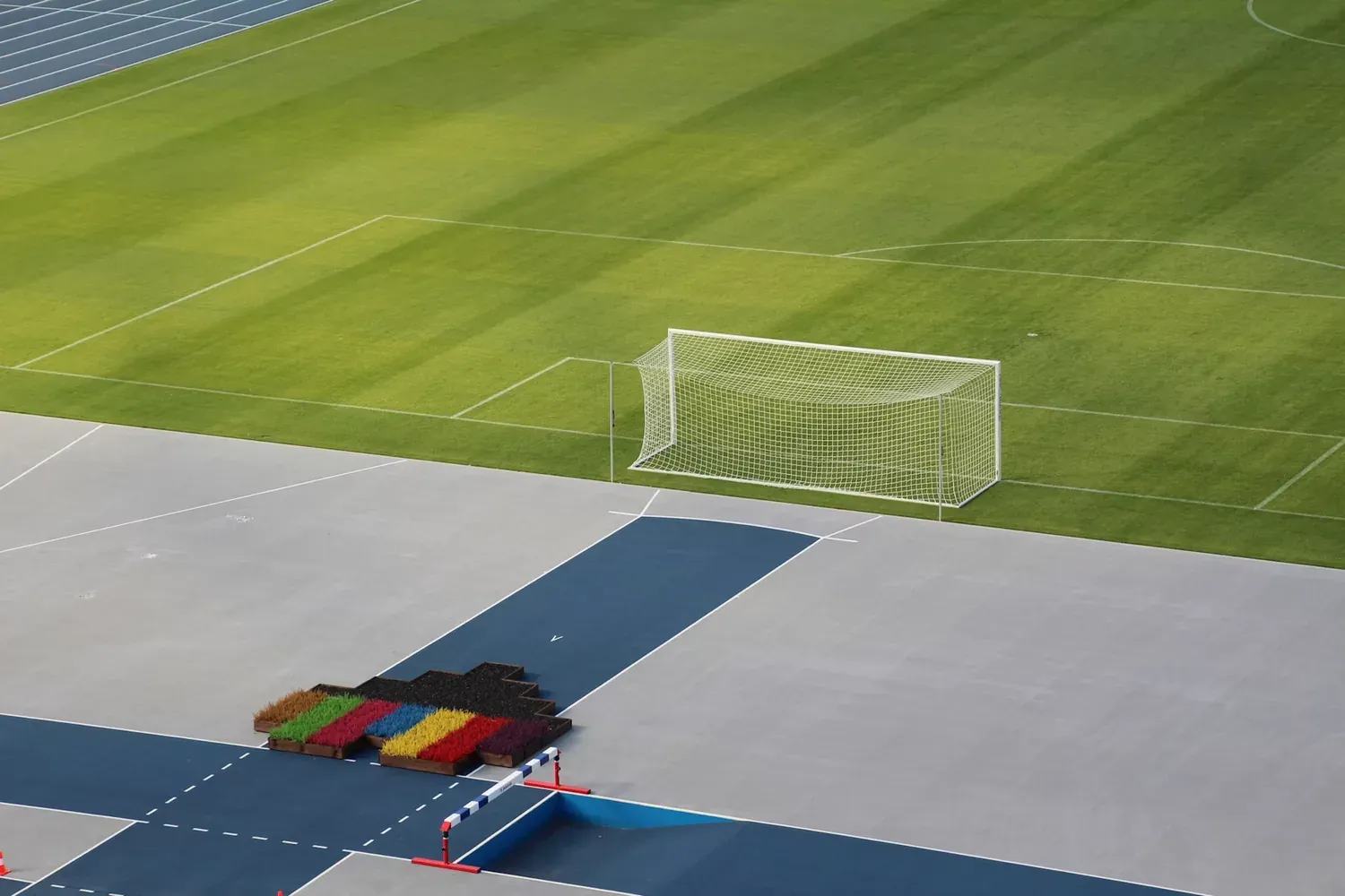 Terrain de football et piste d’athlétisme vides, illustrant les activités sportives à discuter après une lésion du genou